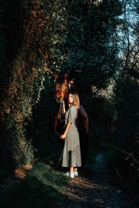 Full length portrait of woman with horse standing in forest