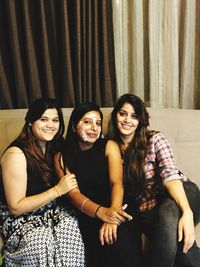 Portrait of female friends sitting on sofa at home