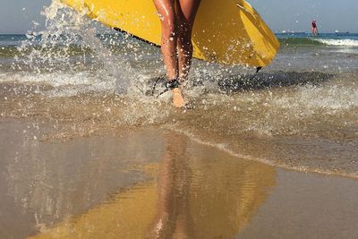 Low section of woman splashing water in sea