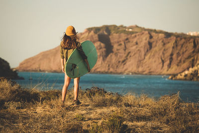 Rear view of woman standing by sea against sky