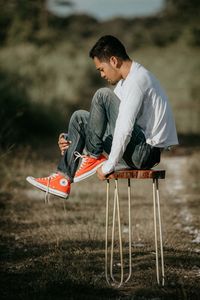 Young man looking away while sitting on land