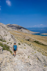 High angle view of woman hiking on mountain against blue sky