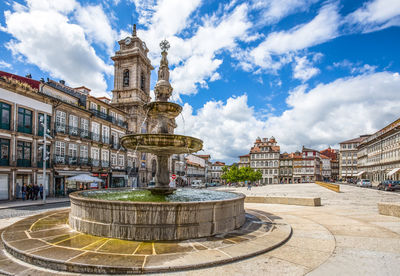 Fountain in city against sky