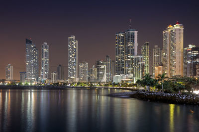 Illuminated buildings in city against sky at night