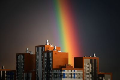 Low angle view of rainbow over buildings at night