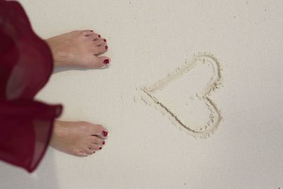 Feet in front of heart on sand