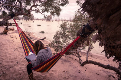 Woman using digital tablet while relaxing in hammock