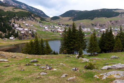 Scenic view of landscape by lake and mountains against sky