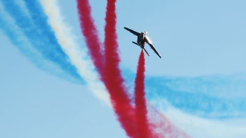 Low angle view of airplane flying against clear blue sky