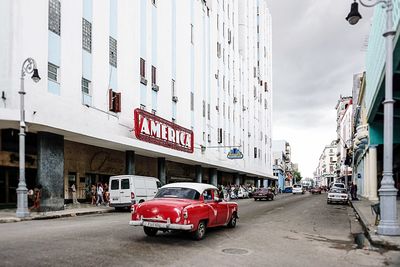 Cars on city street against sky