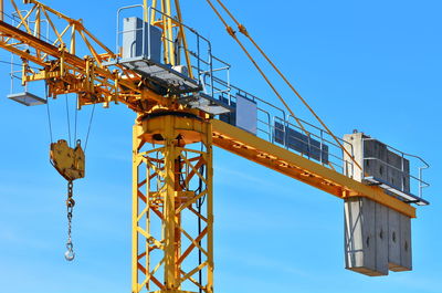 Low angle view of crane against clear blue sky