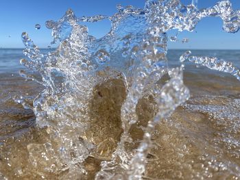 Close-up of water splashing in sea against sky