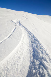 Aerial view of snowcapped landscape against blue sky