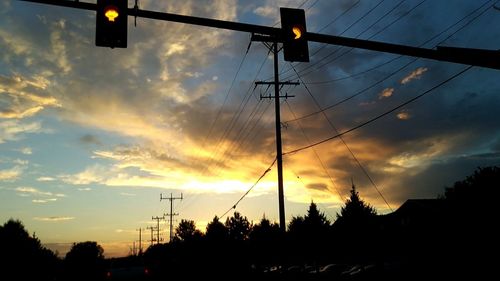 Low angle view of silhouette electricity pylon against sky during sunset