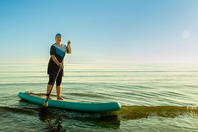 Rear view of man surfing in sea against sky