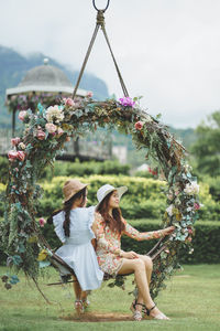 Friends sitting together on swing in park