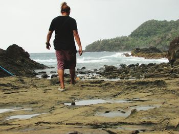 Full length of man walking on beach against clear sky