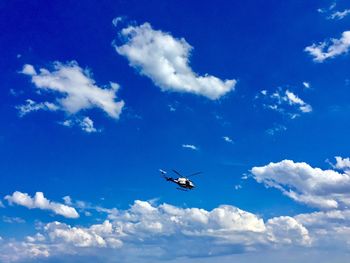 Low angle view of helicopter flying in blue sky