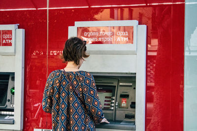 Rear view of woman standing against red wall