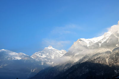 Scenic view of snowcapped mountains against blue sky