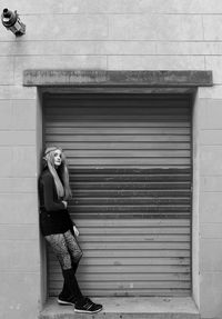 Full length of woman standing by closed shutter