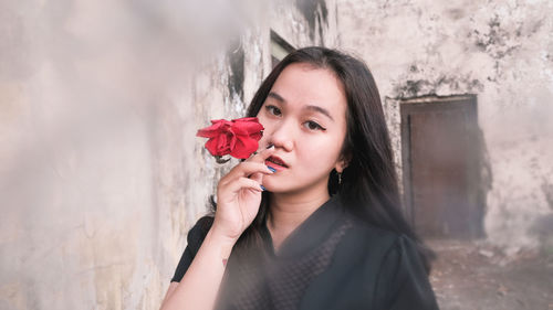 Portrait of beautiful woman holding red flower