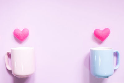 Cup with heart shape decorations over pink background