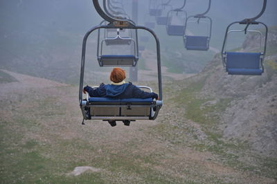 Senior woman sitting on cable car while riding over scenic landscape of italian dolomites