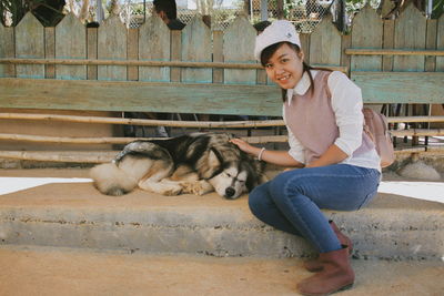 Portrait of smiling young woman sitting by dog on staircase