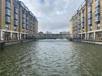 Canal amidst buildings in city against sky
