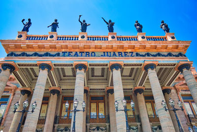 Low angle view of statues on building against sky