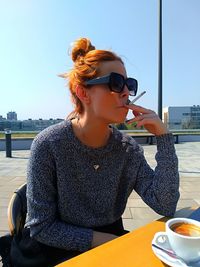 Young woman wearing sunglasses sitting on table