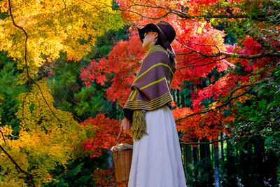 Rear view of woman standing against trees during autumn