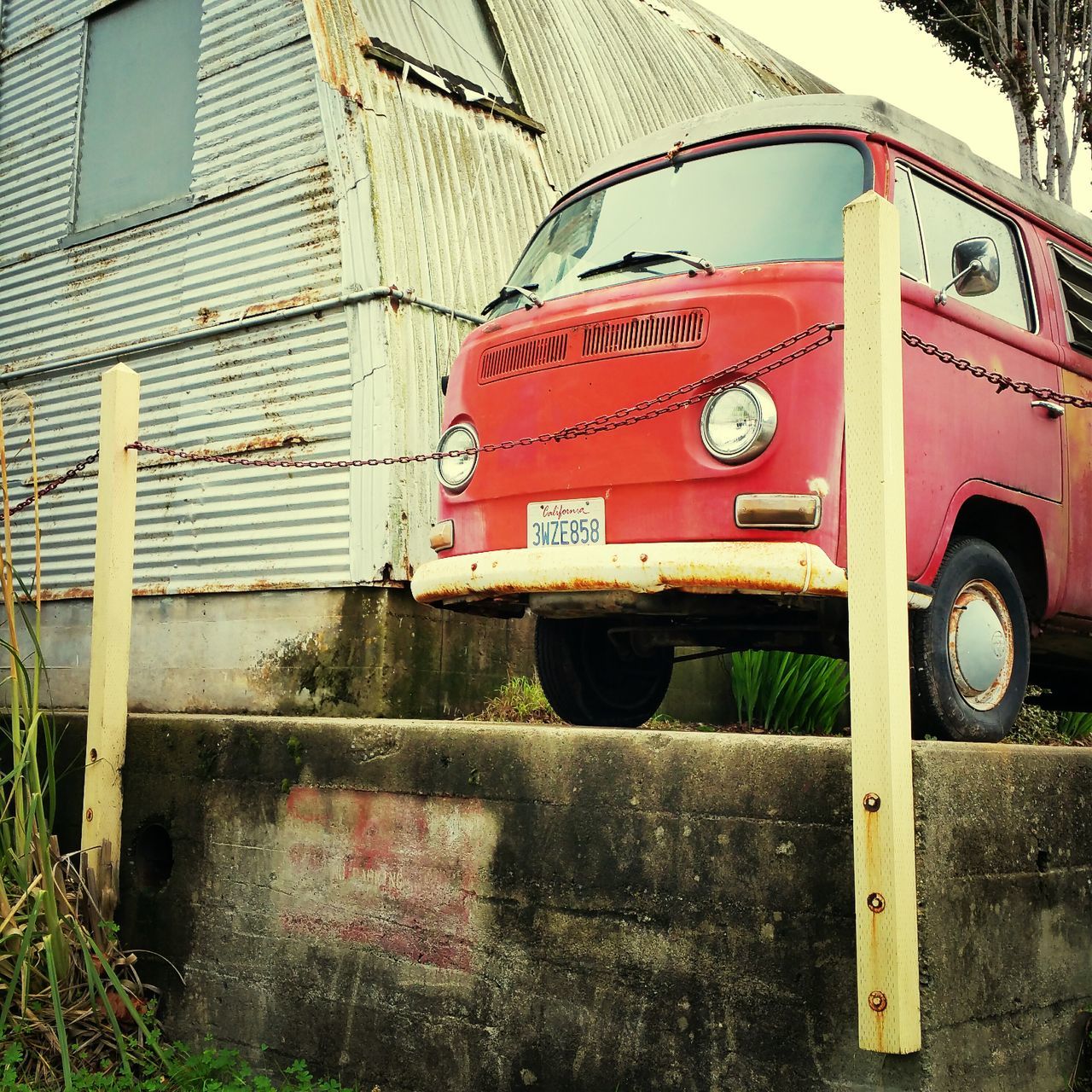 built structure, architecture, building exterior, transportation, day, outdoors, mode of transport, land vehicle, red, metal, no people, wall - building feature, brick wall, abandoned, grass, yellow, old, street, protection, safety