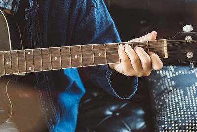 Midsection of man playing guitar at home