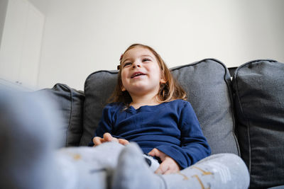 Smiling girl holding joystick playing game sitting on sofa