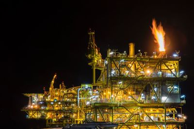 Night offshore view at oil and gas platform with a lot of lights and flare tip burning.