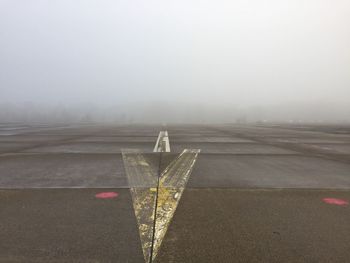 Empty airport runway against foggy sky