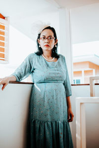 Portrait of young woman standing against wall