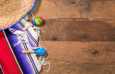 Directly above shot of serape with sombrero and maracas on wooden table