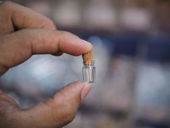 Close-up of person holding glass bottle with cork