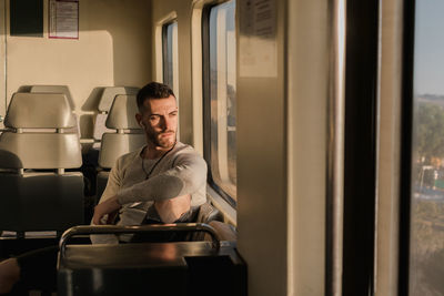 Thoughtful young male passenger listening to music in subway car