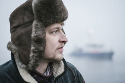 Close-up of young man in fur hat during winter