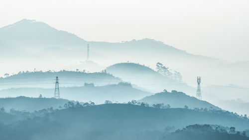 Scenic view of mountains in foggy weather against sky