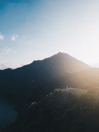 Man standing in the mountains with sunlight and lake