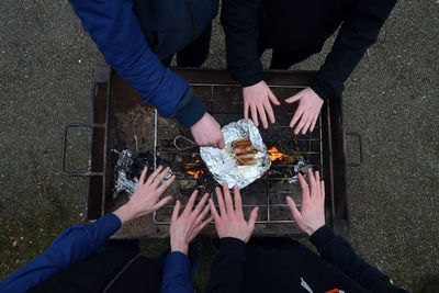People warming hands by barbecue grill