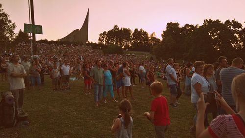 Crowd in park against sky during sunset