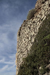 Low angle view of stone wall against sky