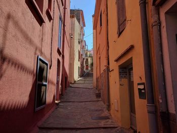 Alley amidst houses against sky