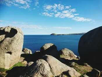 Close-up of rock formation by sea against blue sky